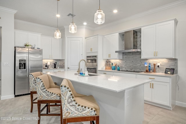 kitchen featuring visible vents, stainless steel appliances, white cabinetry, wall chimney exhaust hood, and a sink