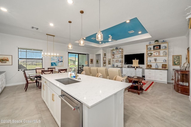 kitchen with visible vents, a sink, a tray ceiling, white cabinetry, and crown molding