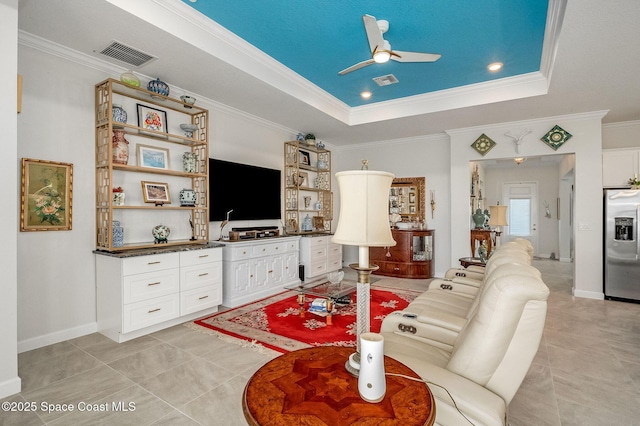 living room with a ceiling fan, baseboards, visible vents, ornamental molding, and a raised ceiling