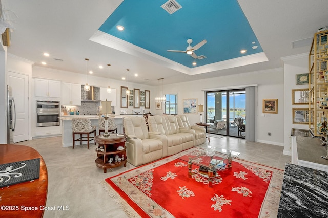 living area featuring visible vents, a ceiling fan, crown molding, and a tray ceiling