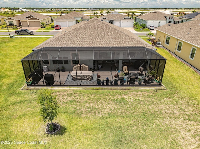 rear view of property featuring a lanai, a residential view, a patio, and roof with shingles