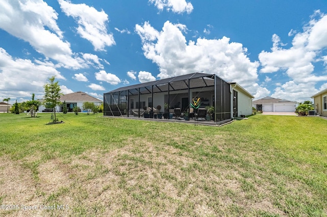 back of house featuring glass enclosure, a detached garage, and a yard