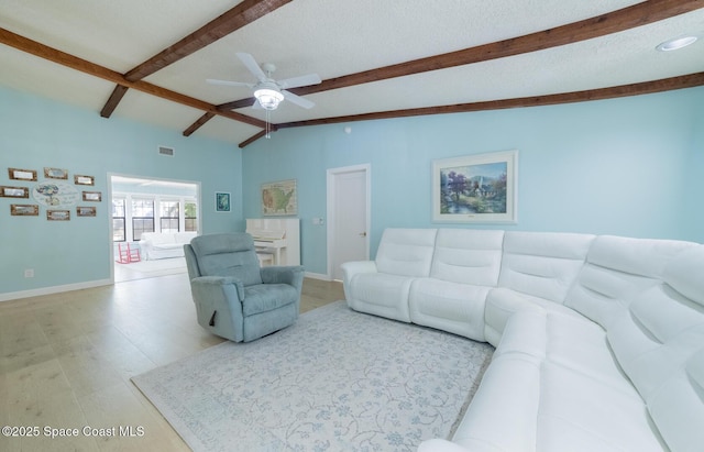 living area featuring vaulted ceiling with beams, a textured ceiling, light wood-style floors, and baseboards