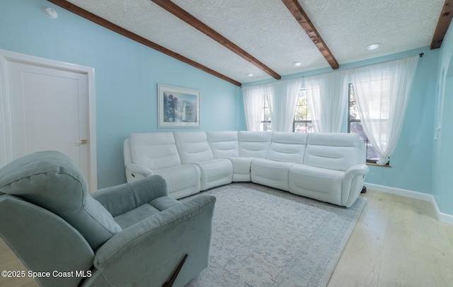 living room with lofted ceiling with beams, wood finished floors, baseboards, and a textured ceiling