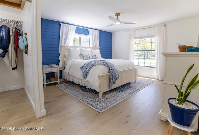 bedroom featuring a closet, light wood-style flooring, baseboards, and a ceiling fan