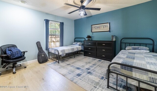 bedroom featuring a ceiling fan, wood finished floors, baseboards, and a textured ceiling