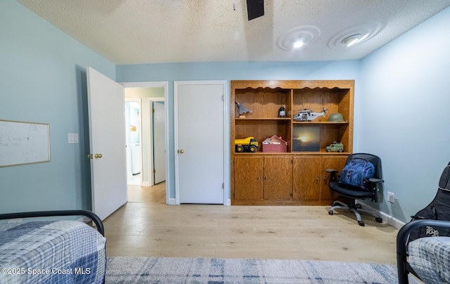 bedroom with light wood-type flooring, baseboards, and a textured ceiling