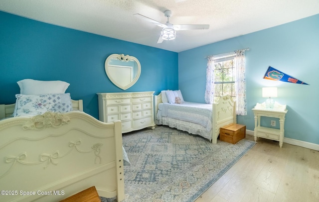 bedroom with baseboards, a textured ceiling, ceiling fan, and hardwood / wood-style flooring