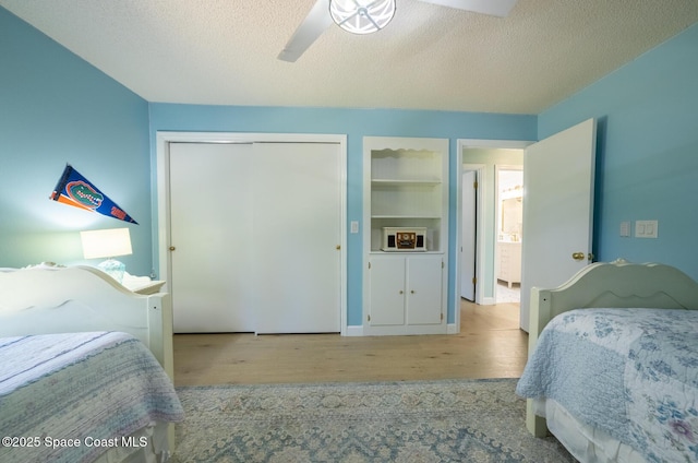 bedroom with ceiling fan, wood finished floors, a closet, and a textured ceiling