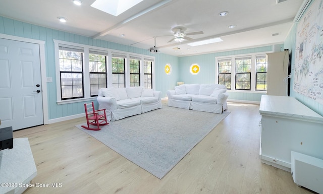 living area with a skylight, plenty of natural light, baseboards, and light wood finished floors