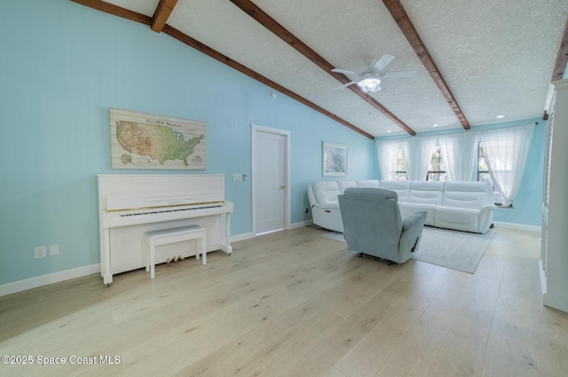 living room featuring vaulted ceiling with beams, baseboards, light wood finished floors, and a textured ceiling