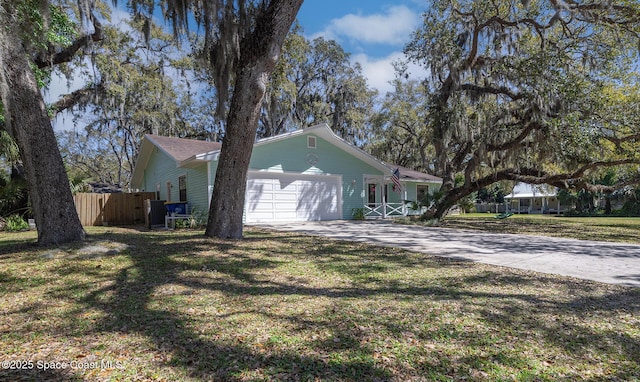 view of side of property featuring a garage, a yard, concrete driveway, and fence