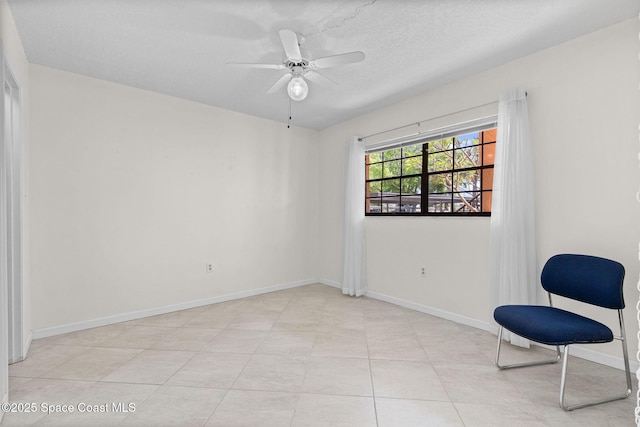 sitting room featuring baseboards, a textured ceiling, and ceiling fan