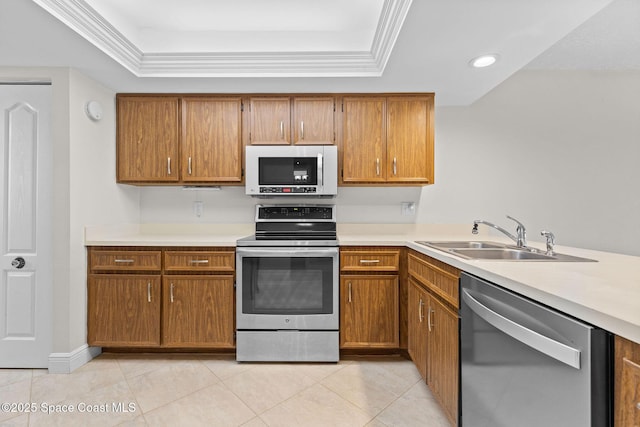 kitchen with a sink, a raised ceiling, appliances with stainless steel finishes, and brown cabinets