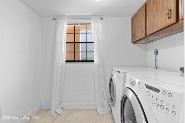 laundry room featuring a textured ceiling, light tile patterned flooring, cabinet space, and washing machine and clothes dryer