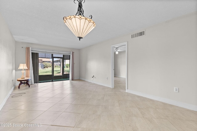 spare room with light tile patterned floors, visible vents, baseboards, and a textured ceiling