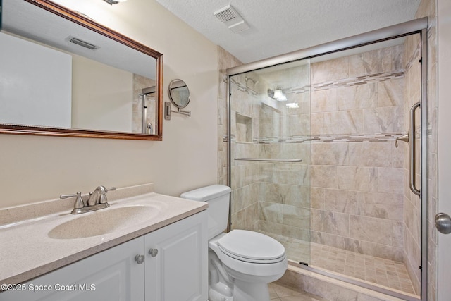 bathroom featuring visible vents, toilet, vanity, a stall shower, and a textured ceiling