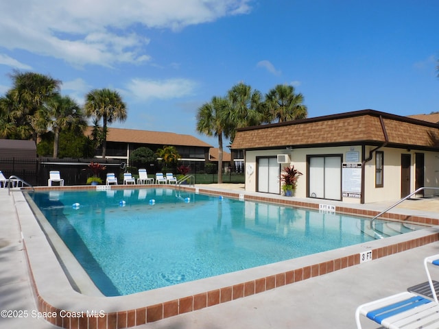 community pool with a patio area and fence