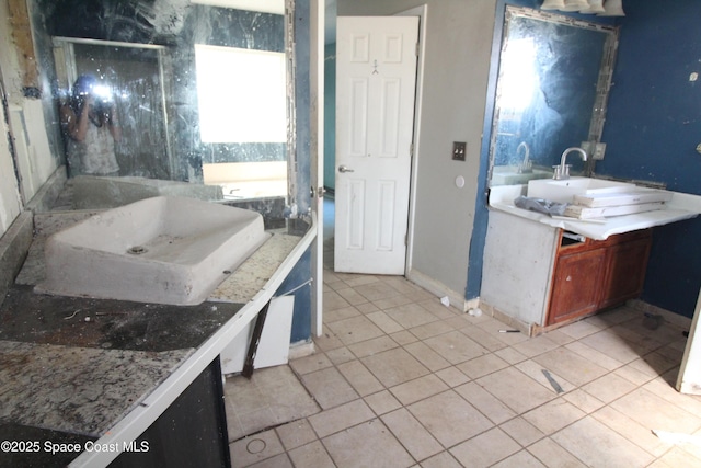 full bath featuring tile patterned flooring, a walk in shower, vanity, and baseboards