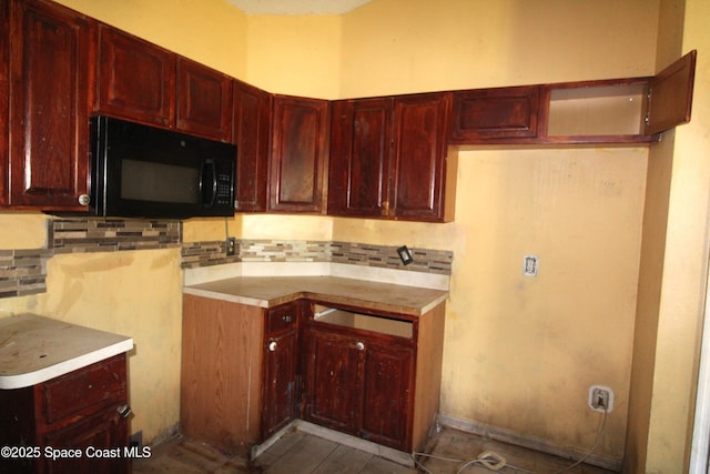 kitchen featuring backsplash, dark brown cabinets, and black microwave