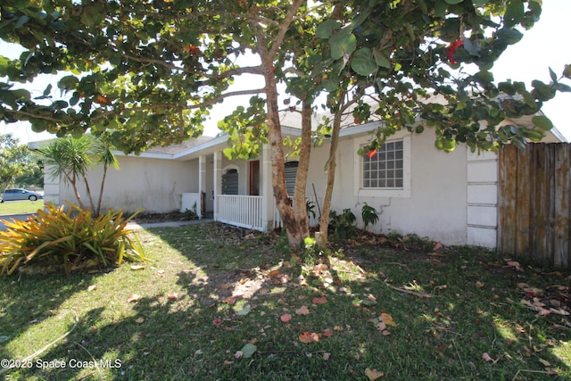 view of property exterior with stucco siding, a lawn, and fence