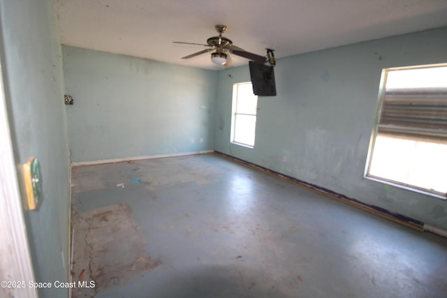 spare room featuring a ceiling fan, concrete floors, and baseboards