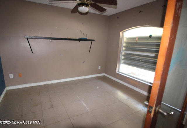 spare room featuring tile patterned flooring, a ceiling fan, and baseboards