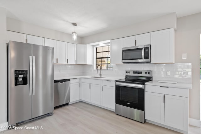 kitchen featuring a sink, stainless steel appliances, white cabinets, and light countertops