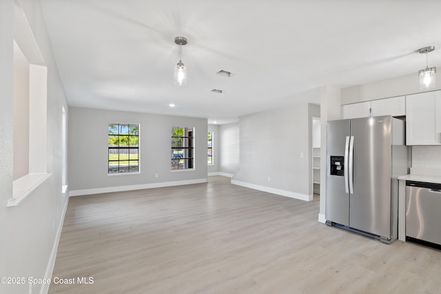 kitchen featuring light wood finished floors, decorative backsplash, hanging light fixtures, white cabinets, and appliances with stainless steel finishes