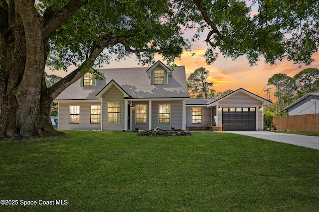 cape cod house with fence, driveway, a shingled roof, a garage, and a lawn