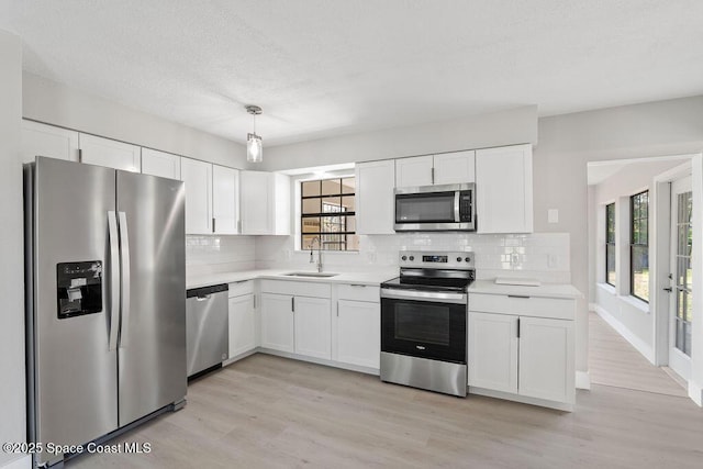 kitchen featuring white cabinetry, light countertops, appliances with stainless steel finishes, and a sink