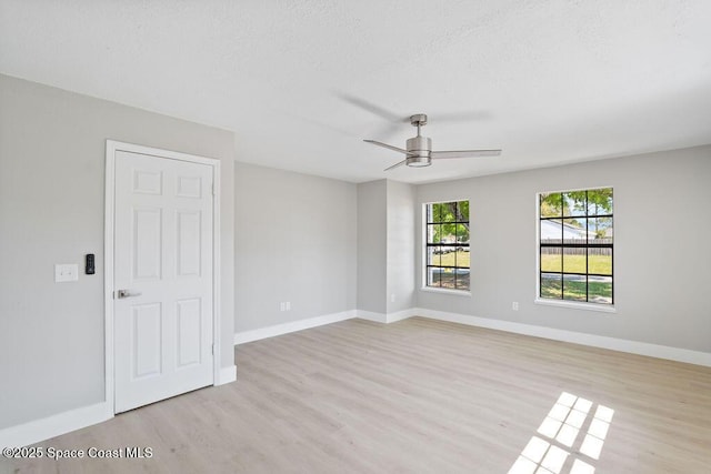 spare room featuring light wood finished floors, baseboards, a textured ceiling, and ceiling fan