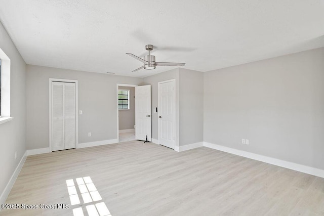 empty room featuring light wood-type flooring, baseboards, and ceiling fan