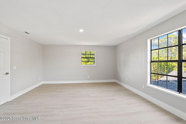 empty room featuring visible vents, baseboards, and light wood finished floors