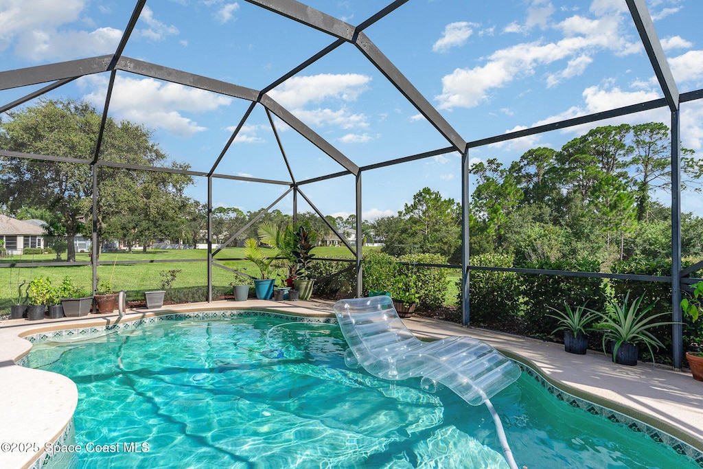 outdoor pool featuring a lanai and a lawn