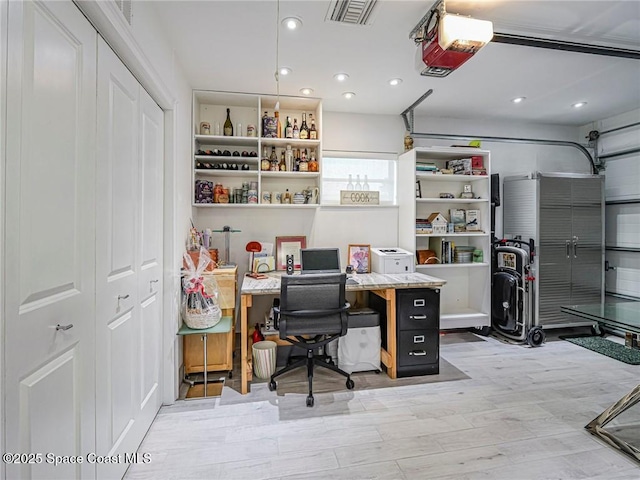 office space featuring wood finished floors, recessed lighting, visible vents, and a garage