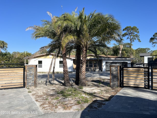 view of front of house with stucco siding, fence, and a gate