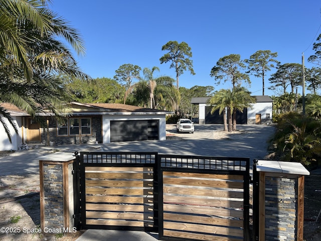 view of front of house with a fenced front yard, driveway, an attached garage, and a gate