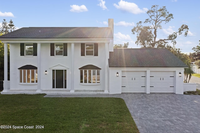 view of front of home with decorative driveway, an attached garage, a front yard, and a shingled roof