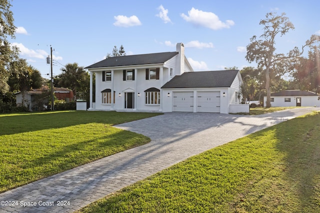 view of front of property featuring stucco siding, decorative driveway, a front yard, a garage, and a chimney