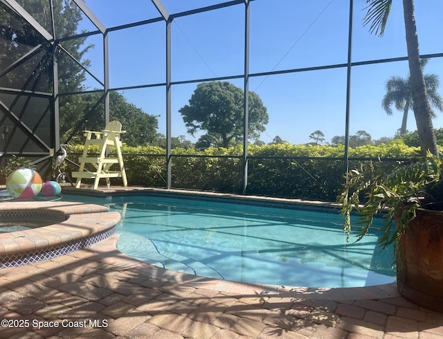 view of swimming pool featuring glass enclosure, a pool with connected hot tub, and a patio