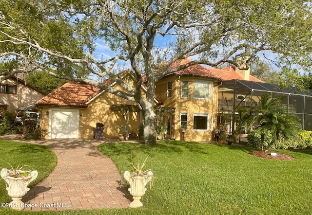 mediterranean / spanish-style house featuring a chimney, a garage, a tile roof, and a front lawn