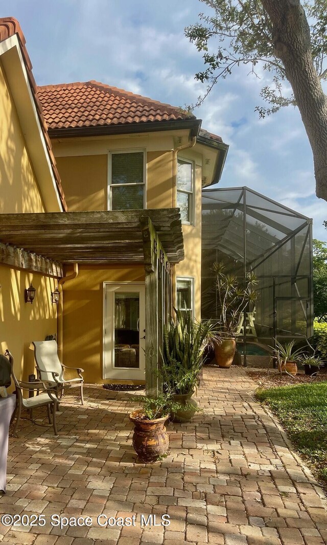 rear view of house featuring a tile roof, a lanai, and a patio area