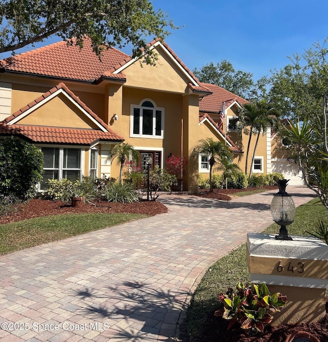 mediterranean / spanish-style home featuring stucco siding, driveway, and a tiled roof