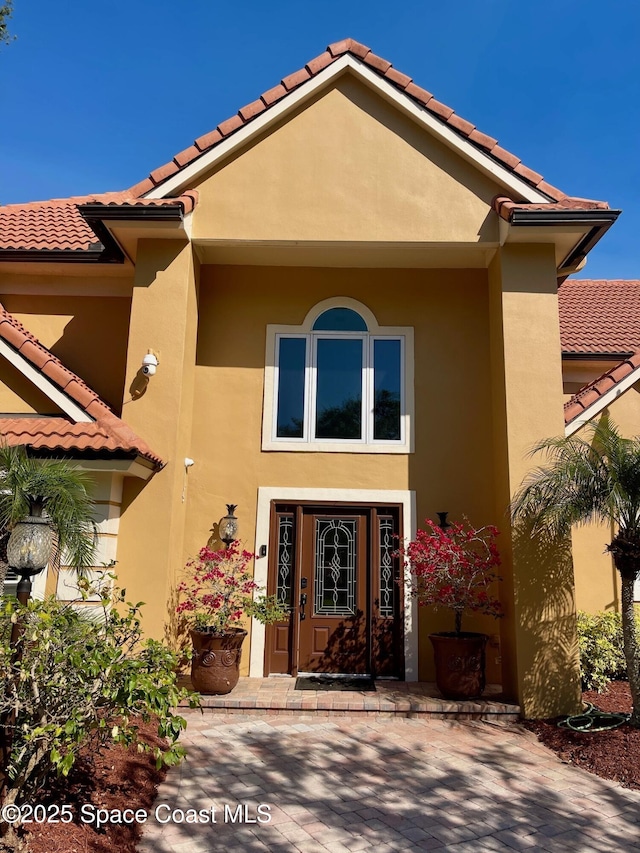 entrance to property featuring a tile roof and stucco siding