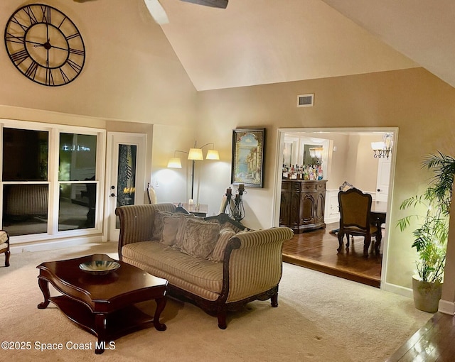 living area featuring baseboards, visible vents, carpet floors, and high vaulted ceiling