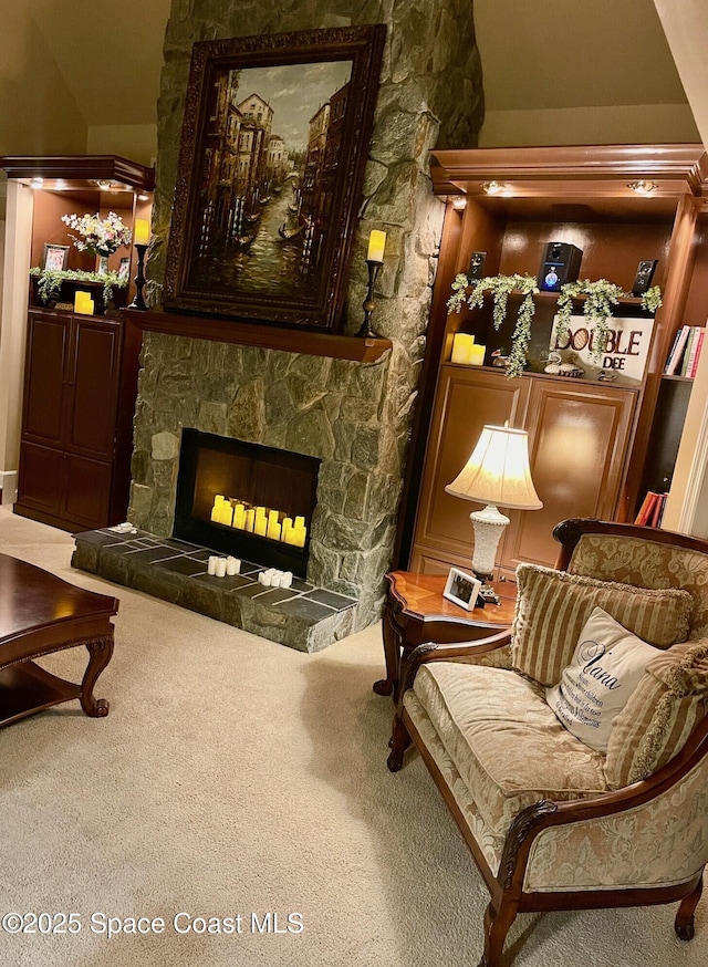 living area featuring a stone fireplace and carpet floors