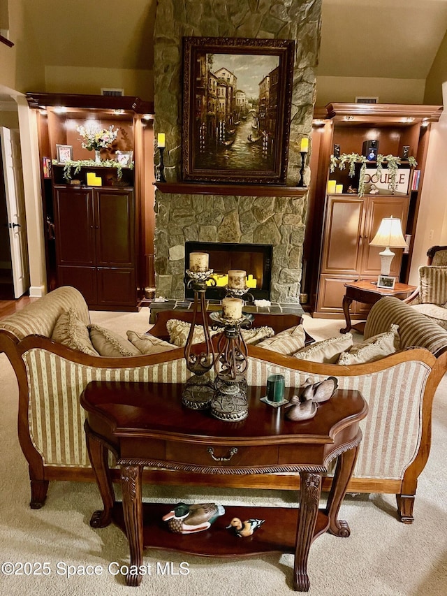 sitting room featuring visible vents, carpet floors, and a stone fireplace