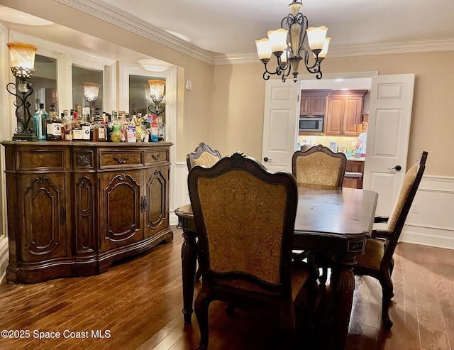 dining room with a chandelier, dark wood-style floors, crown molding, and a dry bar