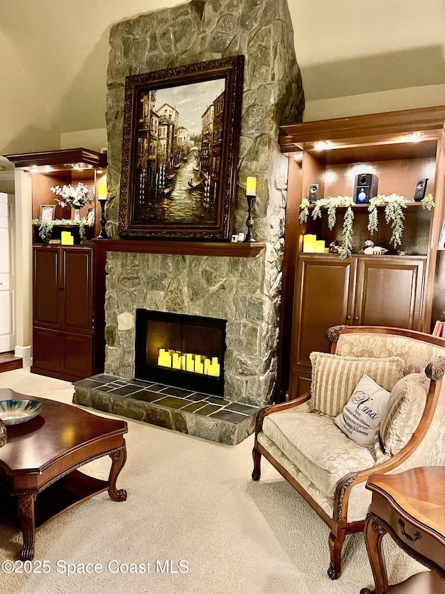 sitting room with carpet floors and a stone fireplace